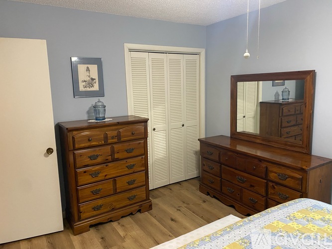 A bedroom with a bed, dresser, and mirror.