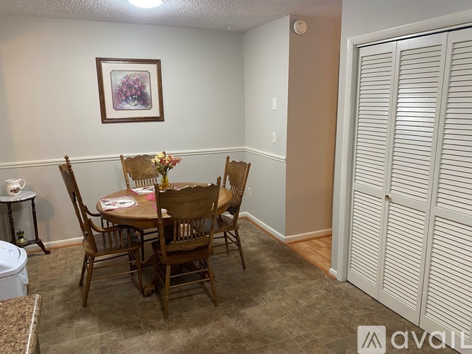 A dining room with a table set for two and a painting on the wall.