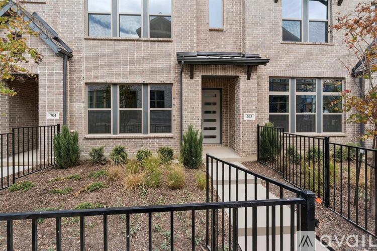 A brick house with a black fence in front.