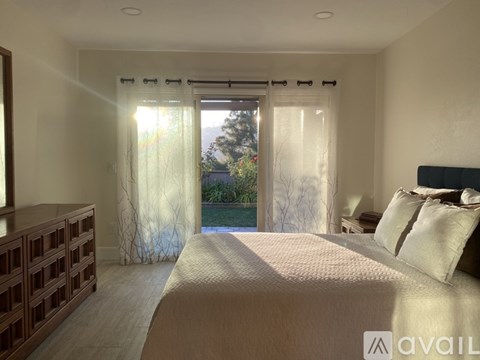 A bedroom with a large bed and a view of the outdoors through the window.