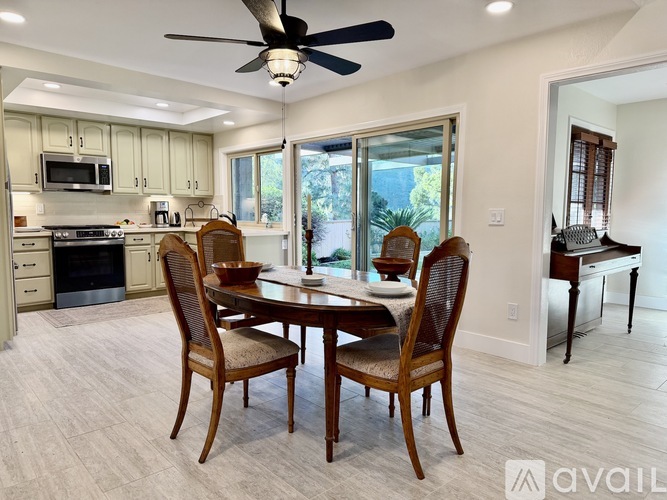 A dining room with a table set for four and a fan in the ceiling.