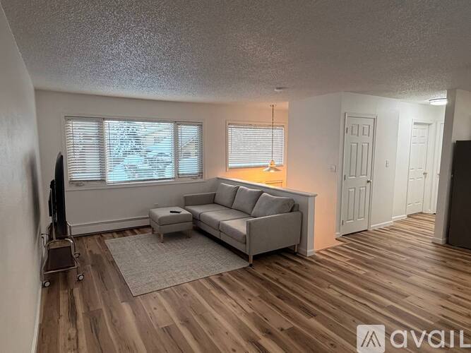 A living room with a grey couch and a wooden floor.