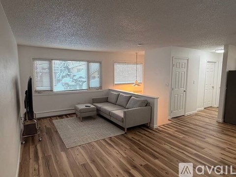 A living room with a grey couch and a wooden floor.