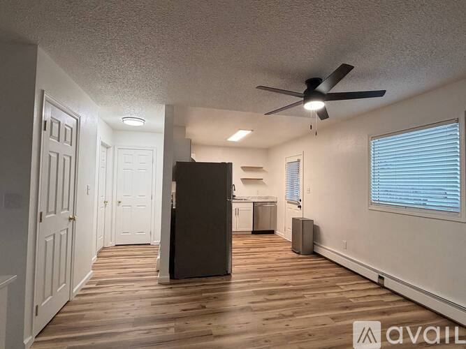 A spacious room with a ceiling fan and wooden flooring.