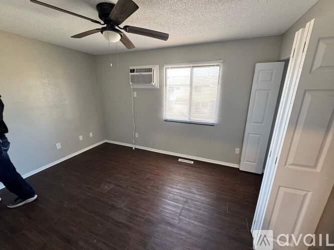 A room with a ceiling fan and a window with blinds.
