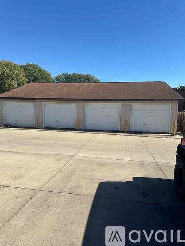 A large garage with a brown roof and four white doors is available for rent.