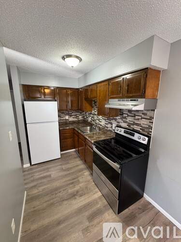 A kitchen with a black stove top oven and wooden cabinets.