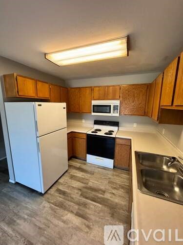 A kitchen with a white refrigerator, a microwave, a stove, and a sink.