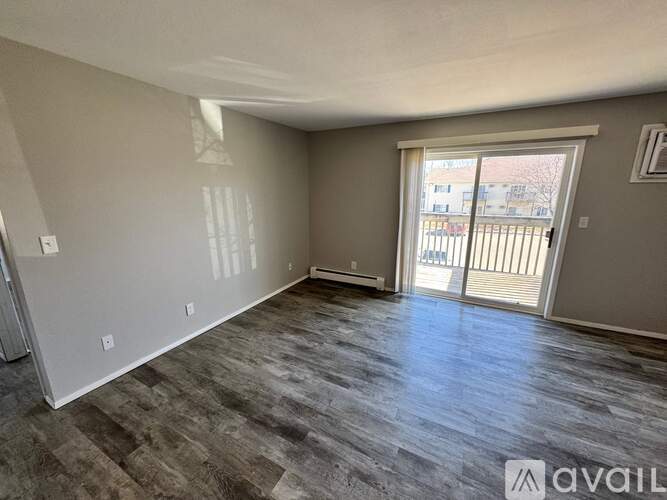 A spacious room with a large window and a sliding glass door leading to a balcony.