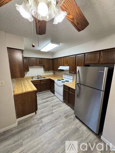 A kitchen with wooden cabinets and a stainless steel refrigerator.