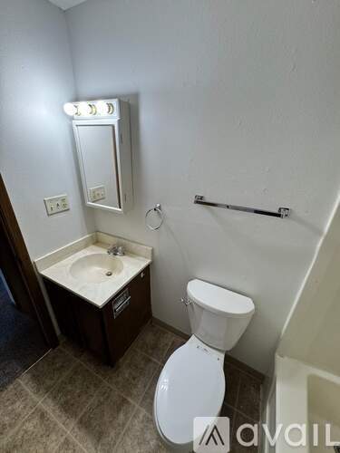 A small bathroom with a toilet, sink, and mirror.