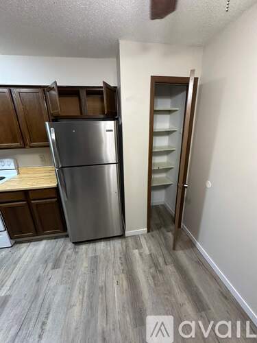 A kitchen with a stainless steel refrigerator and wooden cabinets.