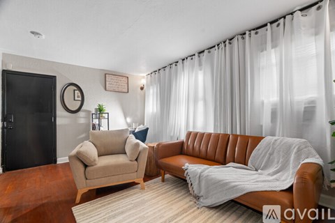 A living room with a brown leather couch and a beige armchair.