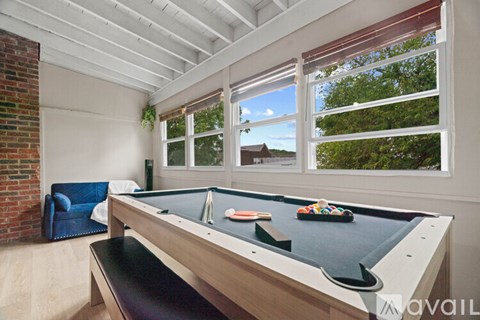 A pool table in a room with a brick wall and a blue couch.