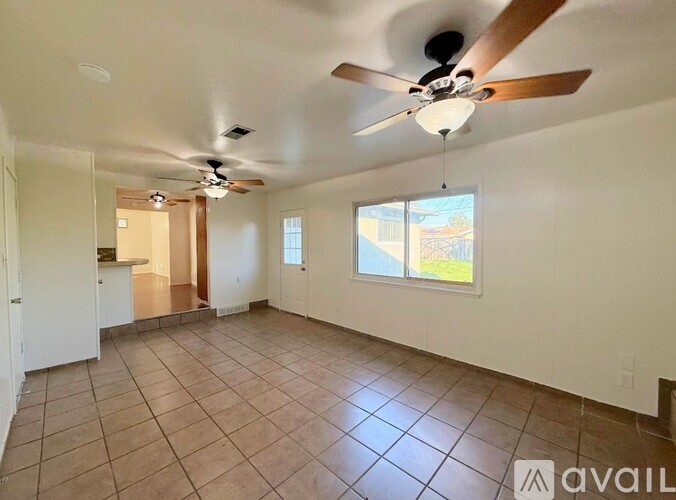 A spacious room with a ceiling fan and tiled flooring.