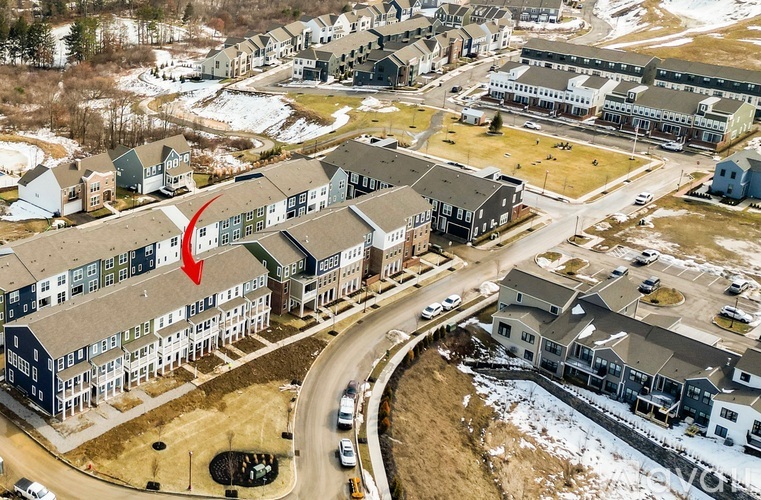 A large building with a red flag on it is surrounded by other buildings.