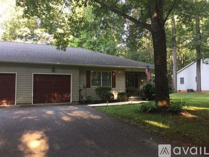 A house with a red garage door is surrounded by trees.