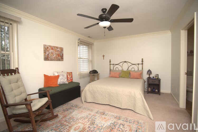 A bedroom with a bed, chair, and a ceiling fan.