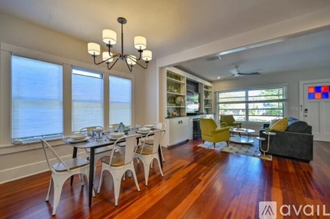 A dining room with a table set for six and chairs around it.