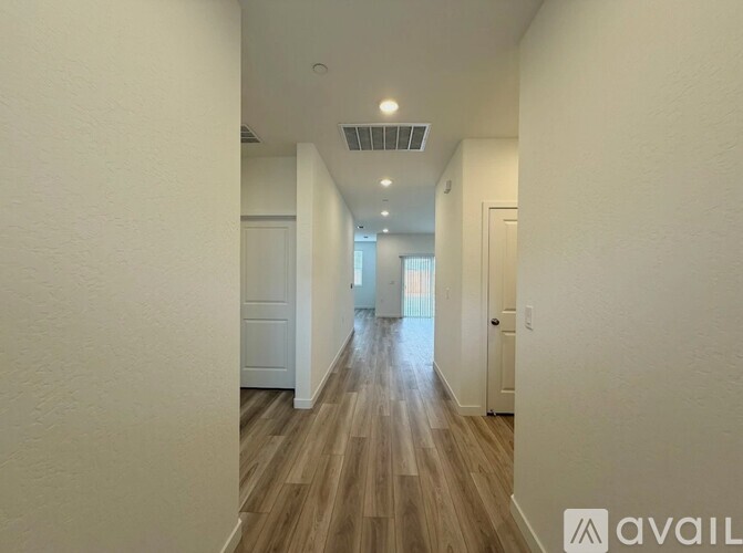A long hallway with wood floors and white walls.