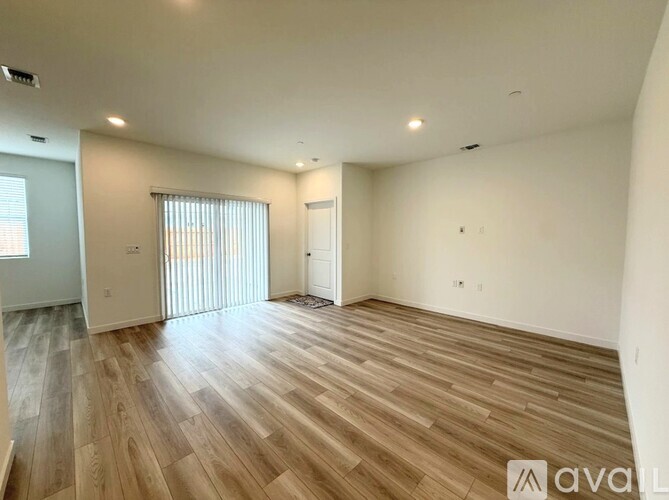 A spacious room with wooden flooring and a sliding glass door.