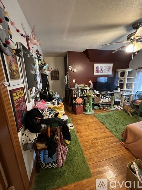 A living room with a green rug and a TV on the wall.