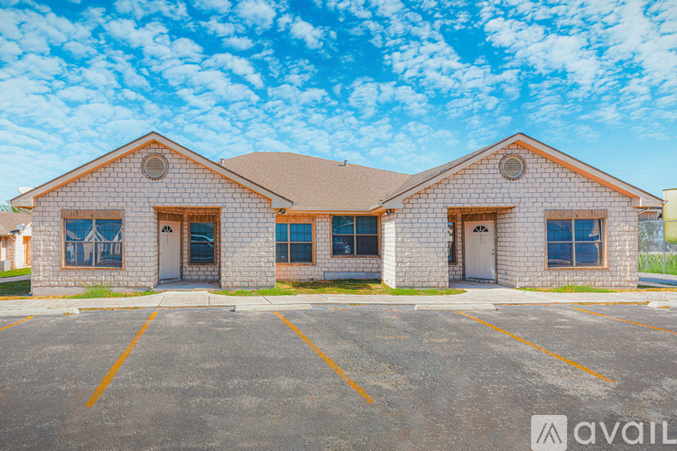 A two-story brick house with a parking lot in front.