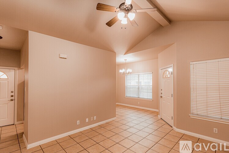 A spacious room with a ceiling fan and tiled flooring.