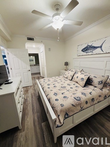 A bedroom with a bed, a ceiling fan, and a painting of a fish on the wall.
