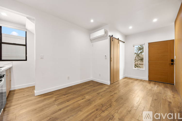 A spacious room with wooden flooring and white walls.
