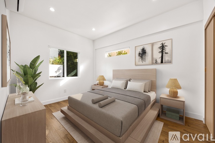 A bedroom with a large bed and a plant on the side table.