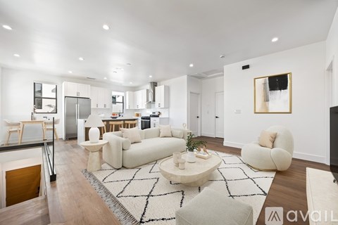 A modern living room with a white sofa set and a black and white rug.