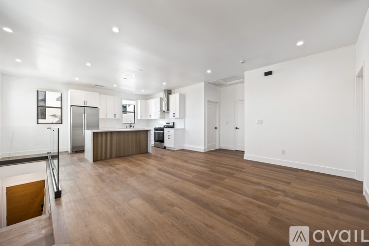 A spacious kitchen with white cabinets and a wooden floor.