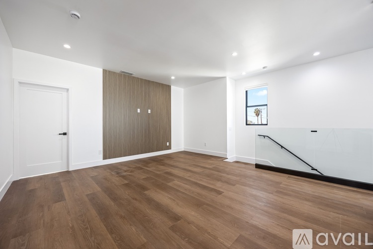 A spacious room with wooden flooring and a window showing a tree.