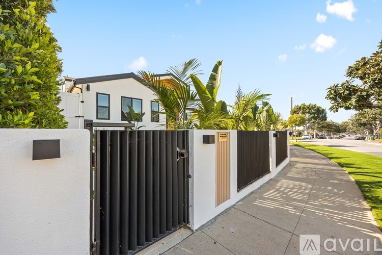 A modern house with a white exterior and a black gate.