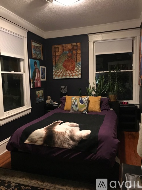 A bedroom with a bed, pillows, and pictures on the wall.