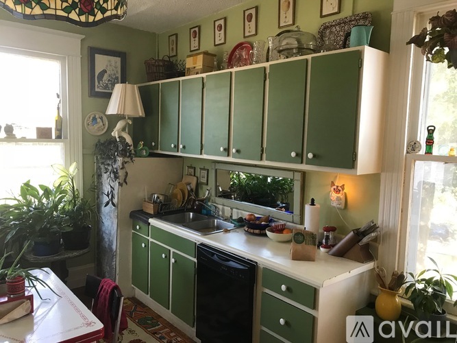 A kitchen with green cabinets and a white counter.