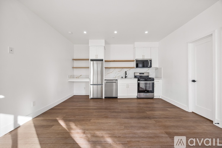 A spacious kitchen with white cabinets and a wooden floor.