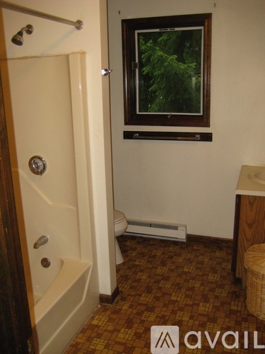 A bathroom with a tub, toilet, and window.