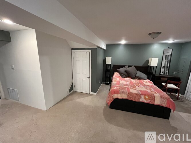 A bedroom with a bed, a chair, and a mirror.