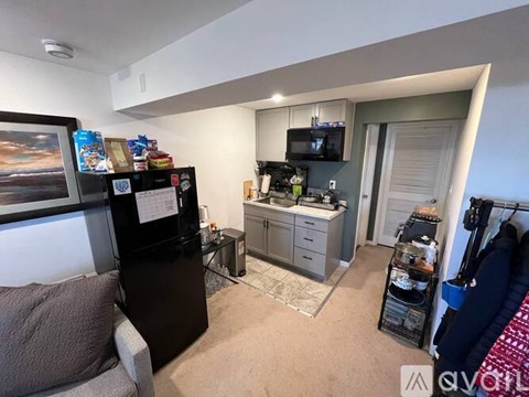 A kitchen area with a fridge, microwave, and a counter with a sink.