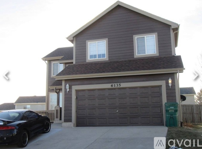 A two-story house with a garage and a car parked in front.