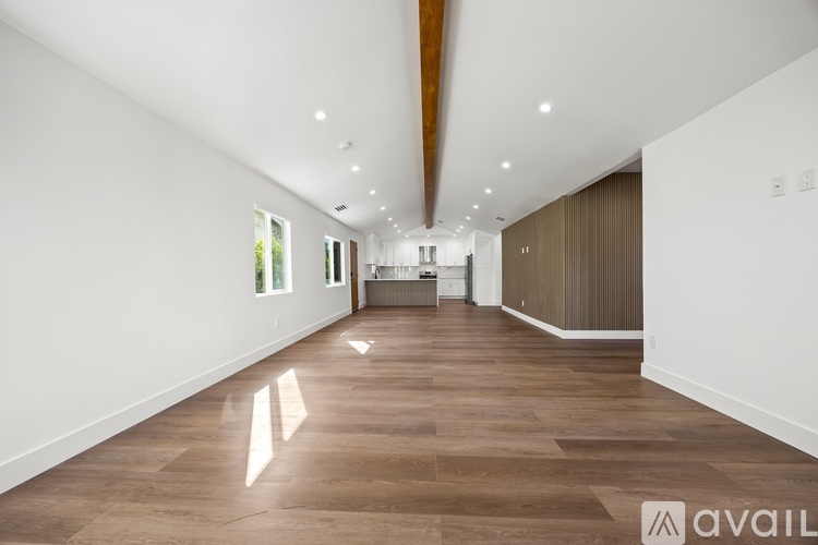A spacious room with wooden flooring and white walls.