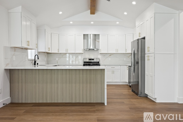 A modern kitchen with white cabinets and a wooden floor.
