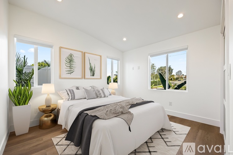A bedroom with a large bed and a plant on the side table.