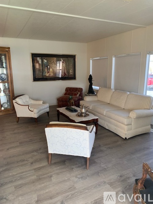 A living room with a white sofa, a wooden coffee table, and a painting on the wall.
