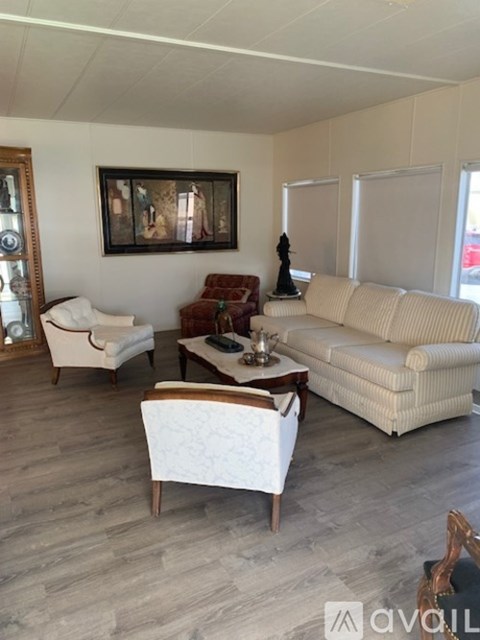 A living room with a white sofa, a wooden coffee table, and a painting on the wall.