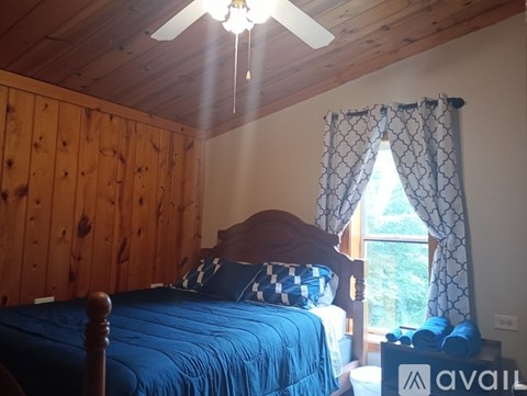 A bedroom with a blue bedspread and wooden walls.
