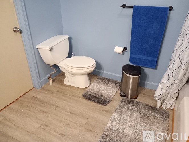 A white toilet sits in a bathroom with a blue wall.