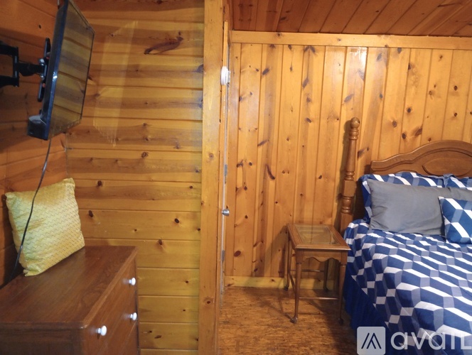 A bedroom with a bed, nightstand, and chair in a wooden cabin.
